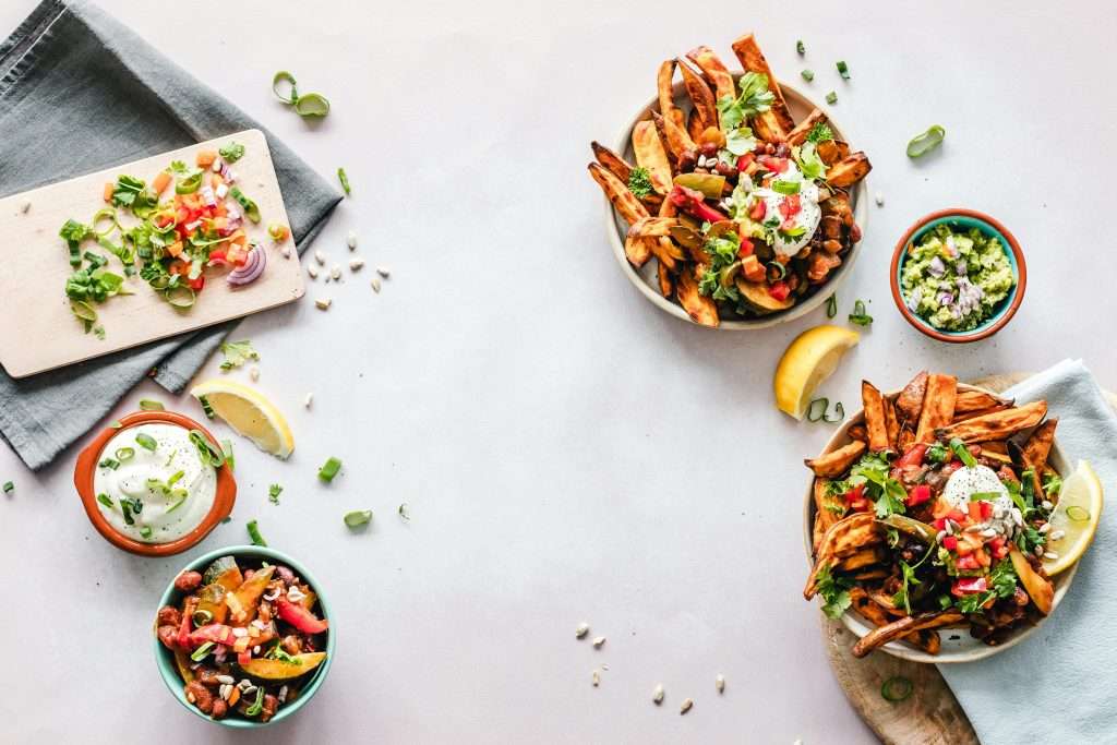 Loaded vegan sweet potato fries with beans, pico de gallo, cilantro, lemon, guacamole, and creamy plant-based sauce
